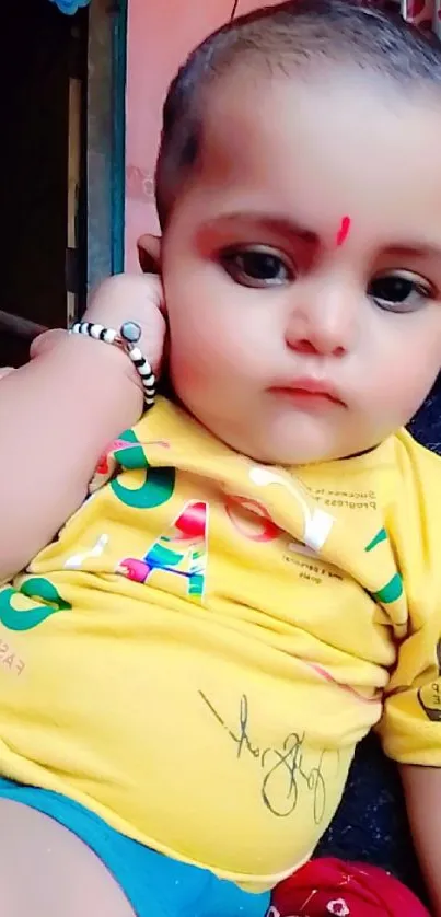 Adorable baby with expressive eyes, wearing colorful attire.