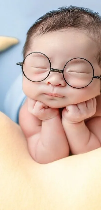 Adorable baby with glasses resting on a soft beige pillow.