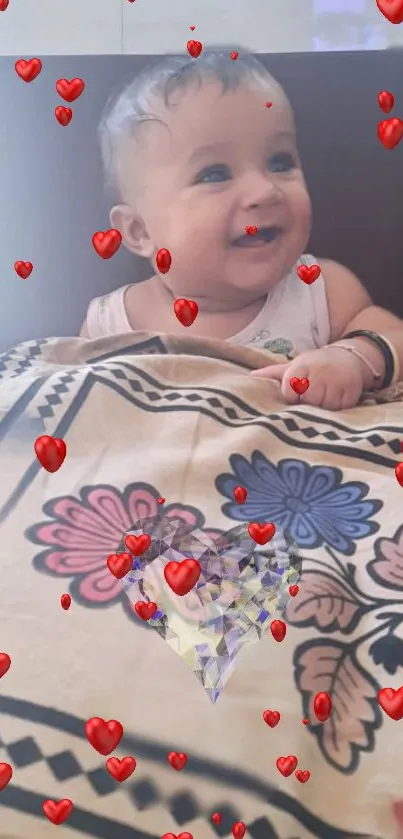 Smiling baby with floating red hearts and floral blanket on a mobile wallpaper.