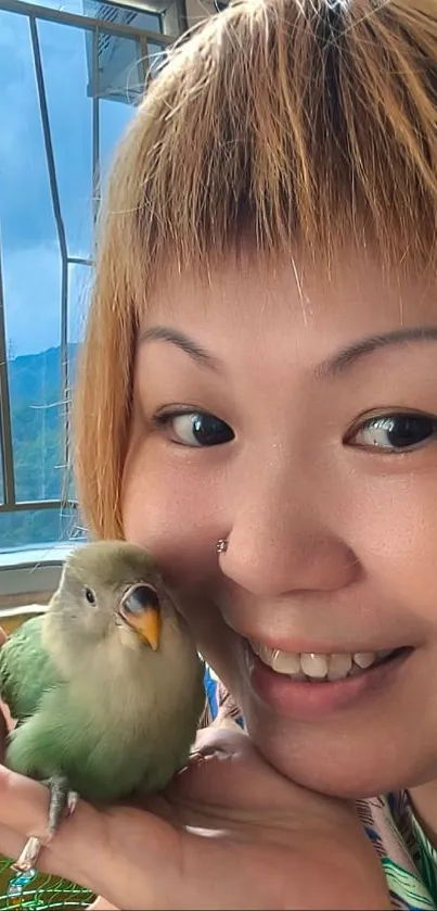 Smiling person holding a cute green bird.