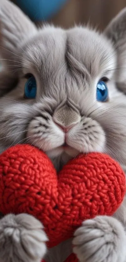 Fluffy bunny with blue eyes holding a red knitted heart.