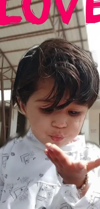 Child blowing a kiss with pink 'LOVE' above.