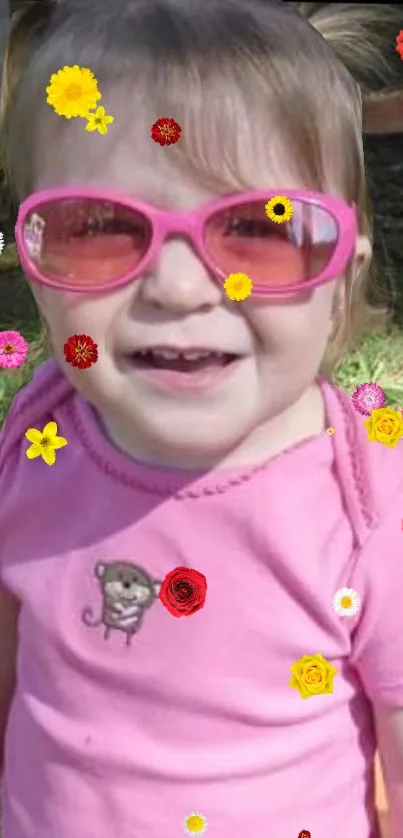 Smiling child with pink sunglasses and floral accents.