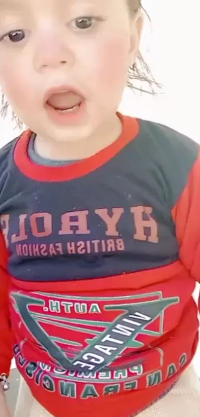 Child in colorful red and blue shirt with open mouth expression.