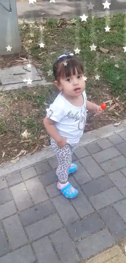 Child in a park with star overlay, wearing colorful shoes.