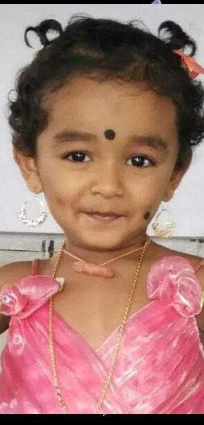Adorable child in pink dress smiling happily.