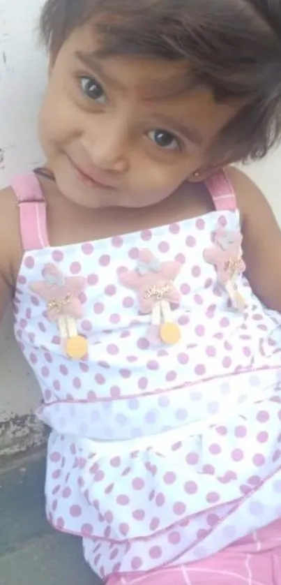 Adorable child with a cute smile in a pink polka dot dress.