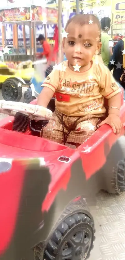 A toddler enjoys a ride in a red toy car at a carnival.