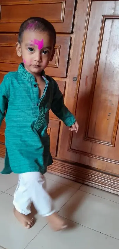 Young child in colorful traditional attire with wooden background.