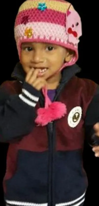 Child wearing a colorful winter hat and jacket on black background.