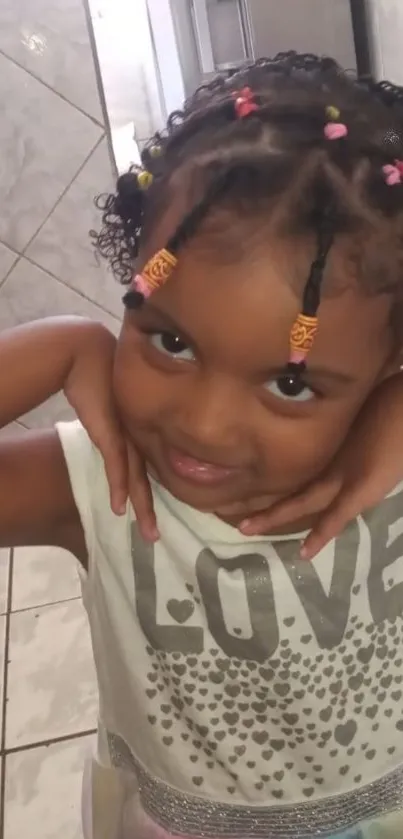 Cute child smiling with colorful beads in hair indoors.