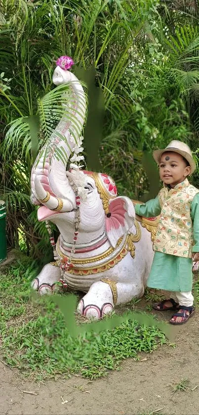 Child in traditional clothes with elephant statue in garden.