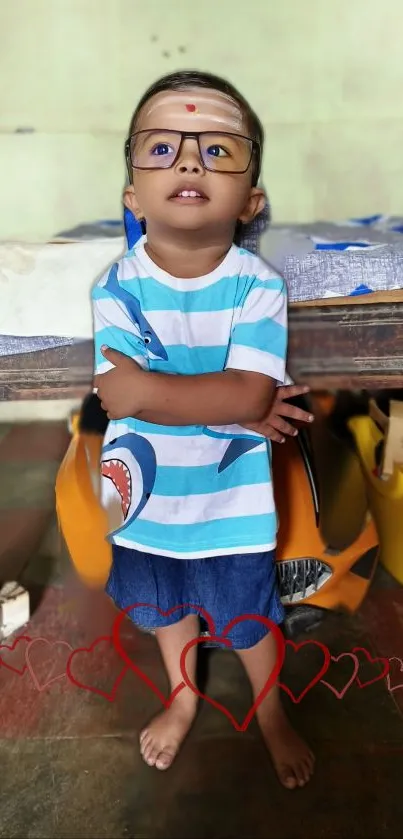 Smiling child with glasses, standing indoors with hearts.