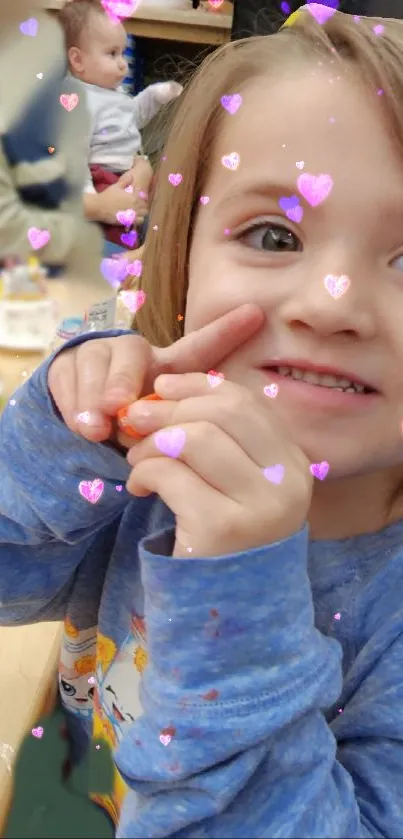 Child in blue sweater with heart effects smiling.