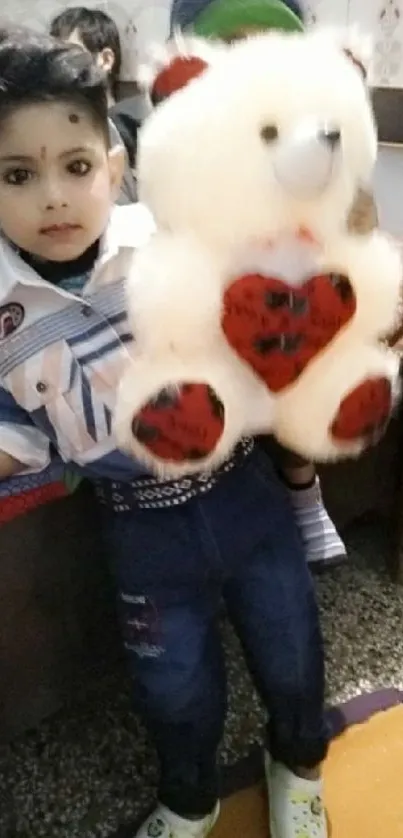 Young child holding a fluffy teddy bear with a heart design.