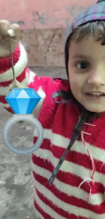 Child holding a diamond ring toy, wearing red stripes.