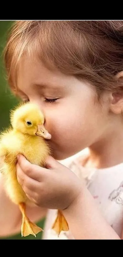 Child lovingly kisses a duckling against a natural green background.