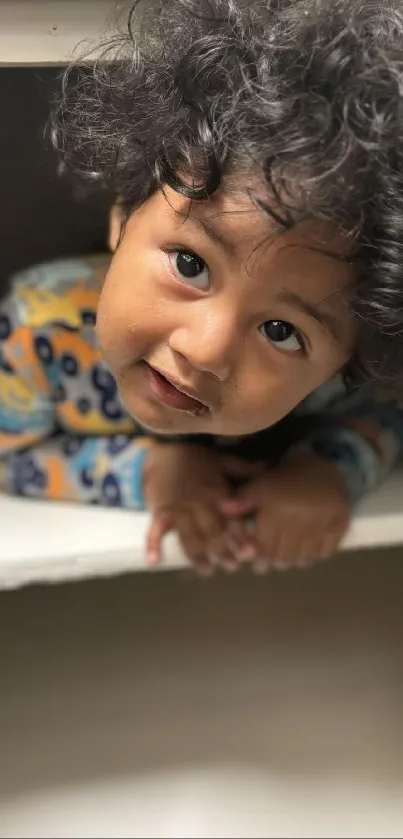 Child with curly hair in a cozy space smiling.