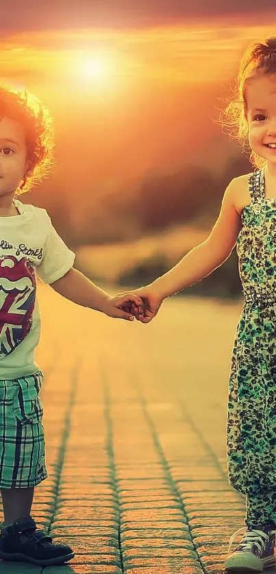 Two young kids smile holding hands in sunset glow.