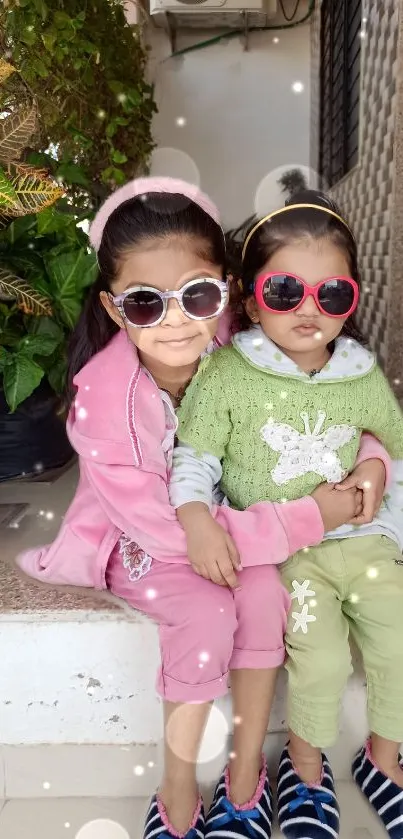 Two smiling children wearing sunglasses and colorful outfits.