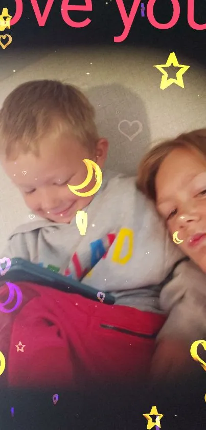 Two children smiling with 'love you' text in a cozy setting.