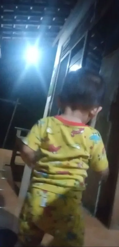 Child in bright pajamas walking indoors at night.