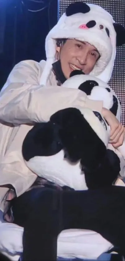 Person in panda costume hugging a panda plush toy.