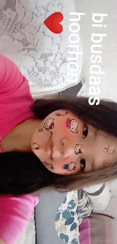 Young girl with cartoon face stickers in a pink shirt.