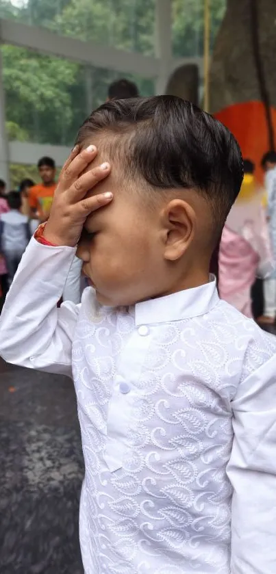 Child in white traditional outfit with a thoughtful pose.