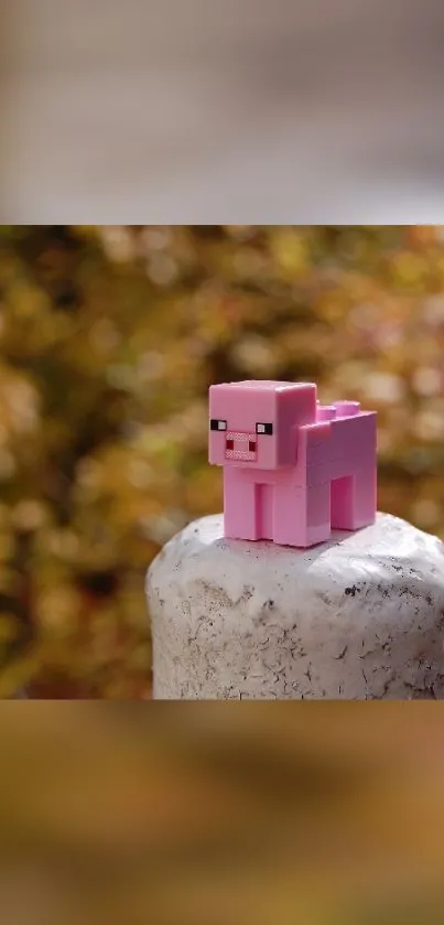 Pink toy pig on a stone pedestal with autumn leaves.