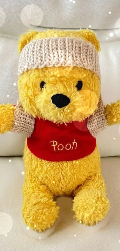 Adorable yellow plush bear wearing a hat and red shirt on a cozy background.