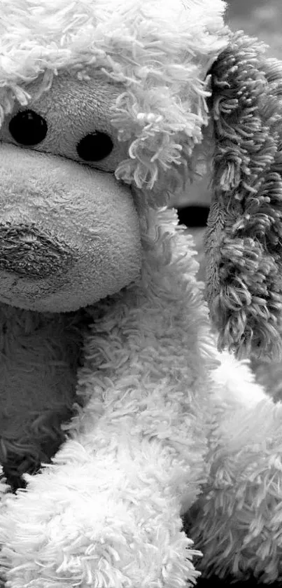 Black and white plush puppy toy sitting on wooden background.