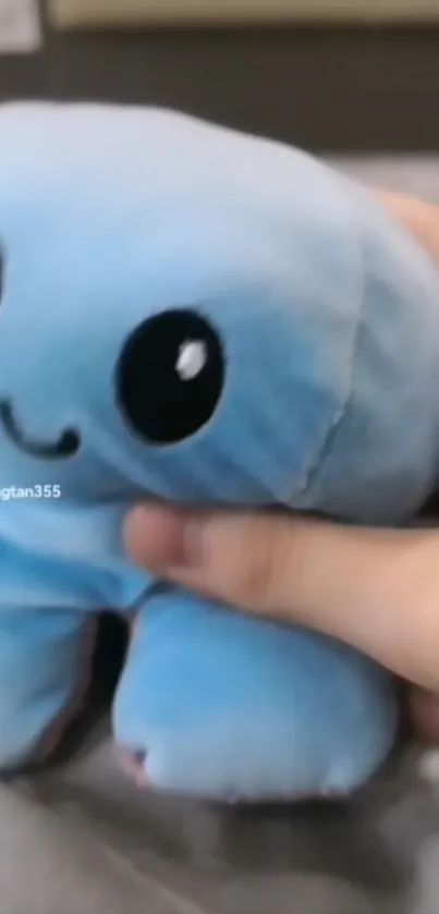 Cute blue plush toy with a smiling face, perfect for mobile wallpaper.