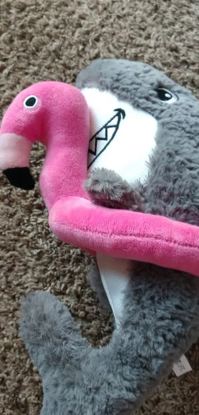 Grey shark and pink flamingo plush on a brown carpet background.