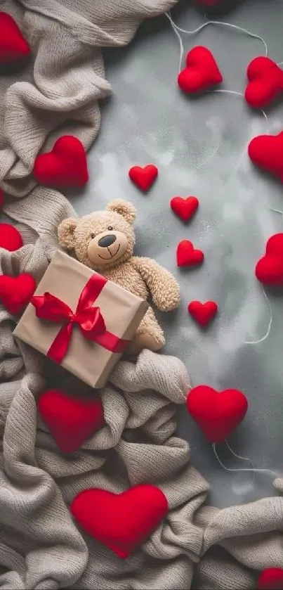 Teddy bear with red hearts and gift box on fabric.