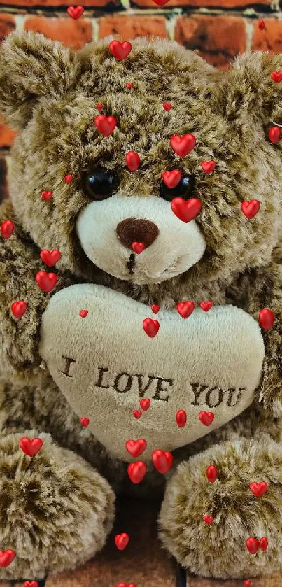 Cute brown teddy bear with "I Love You" heart in front of brick wall.