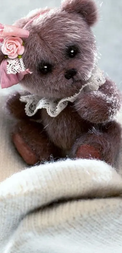 Cute teddy bear with a pink bow sitting on a soft fabric.