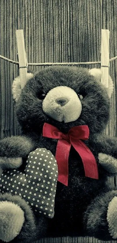 Teddy bear with red bow and heart on wood background.