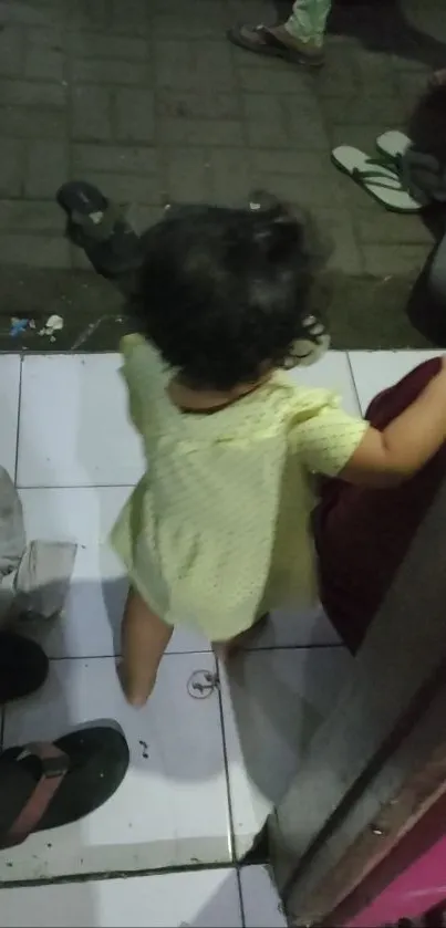 Adorable toddler explores indoors on tile floor, capturing a moment of curiosity.