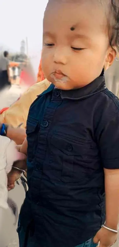 Adorable toddler in a stylish blue shirt with a serene expression.