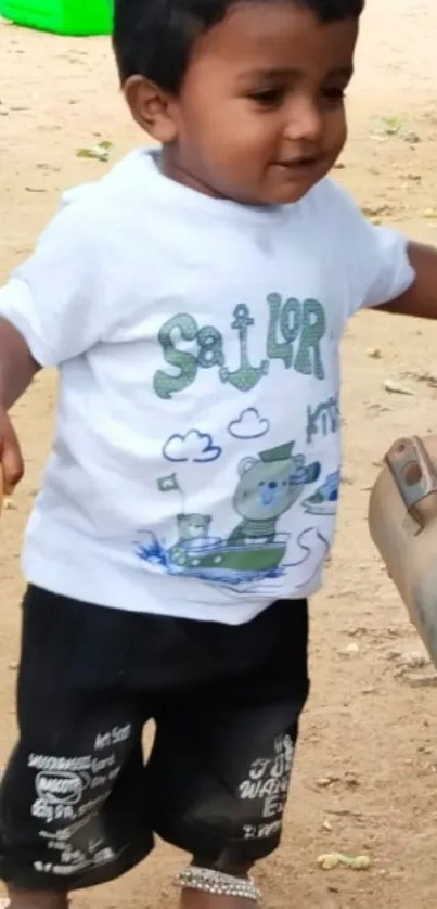 Cute toddler wearing sailor t-shirt, smiling outdoors.