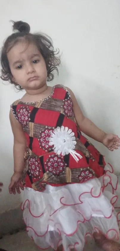 Adorable toddler in a floral dress standing indoors.