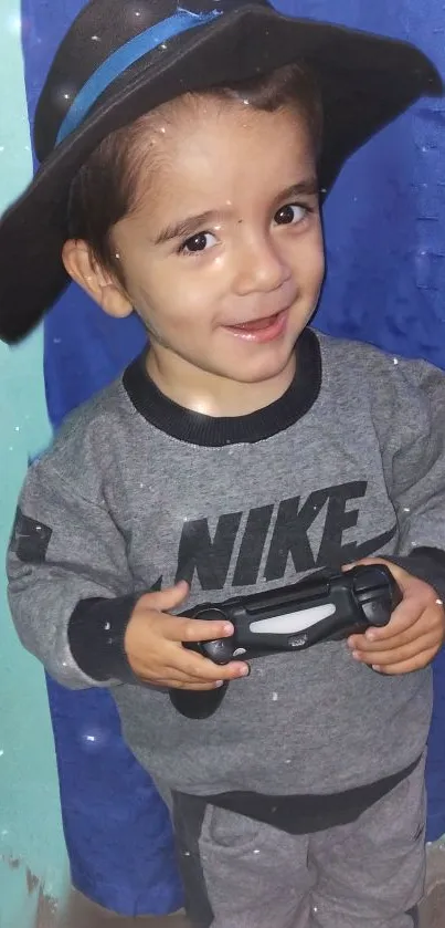 Cute toddler in gray outfit holding a gaming controller and smiling.