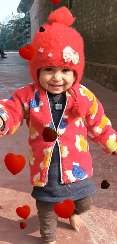 Adorable toddler in red winter jacket walking outdoors with hearts floating around.