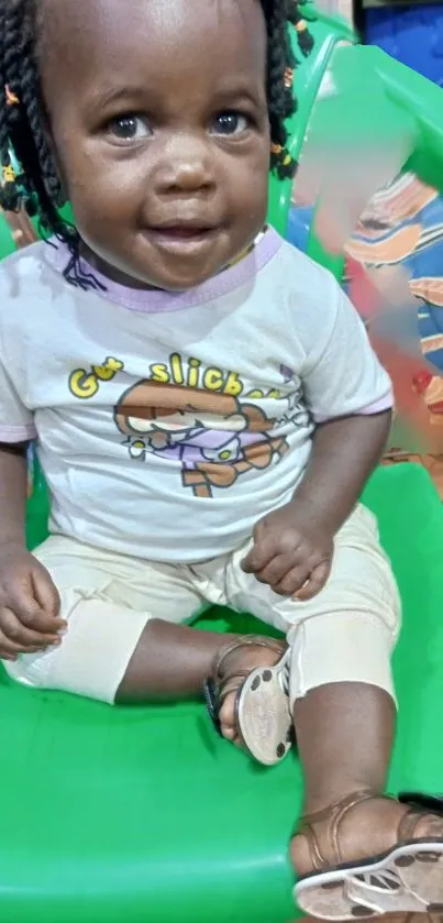 Cute toddler sitting on a green chair smiling.