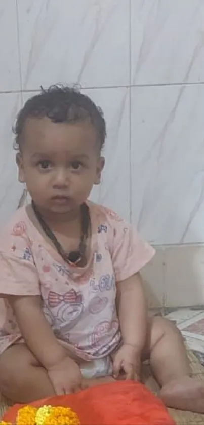 Adorable toddler sitting indoors on mat.