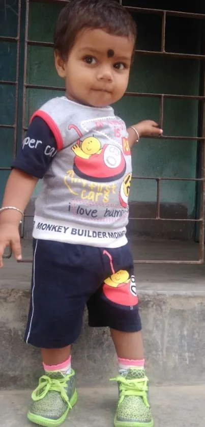 Toddler in colorful clothes standing outside.