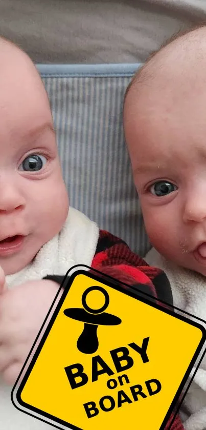 Two cute twin babies with a 'Baby on Board' sign in a mobile wallpaper.