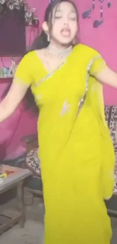 Woman dancing in yellow saree indoors.