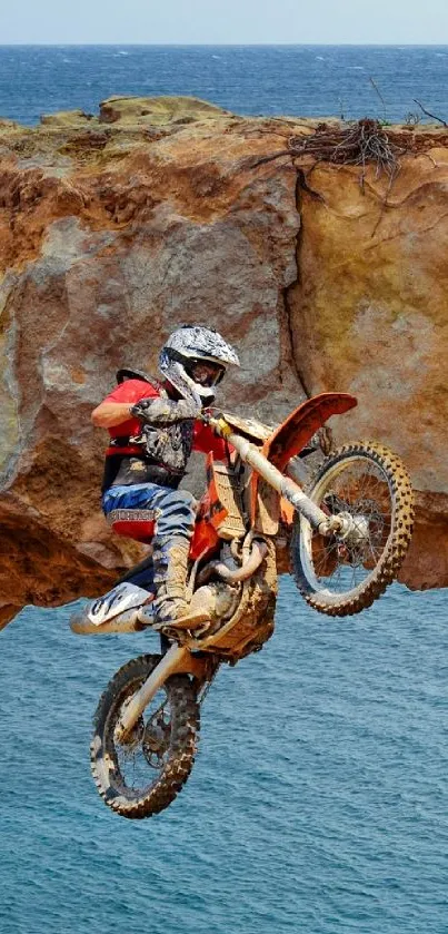 Daring motocross rider jumps rocky arch with ocean view.